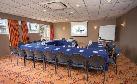 Square shaped room with 20 chairs around tables facing towards a projector at the front of the room.