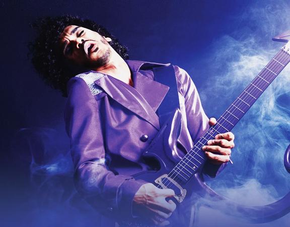 A person dressed in a purple suit passionately plays the guitar in front of a purple background, with a spotlight shining on them.