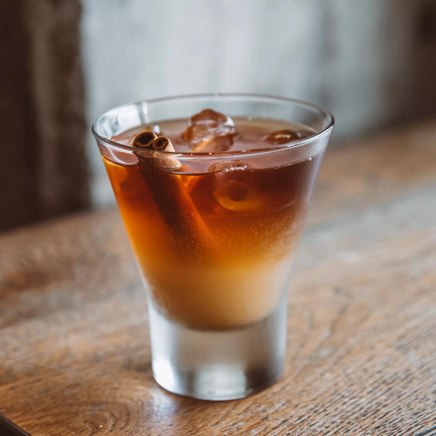 A shot of espresso made by New Chapter, in a shot glass with cinamon sticks inside.