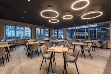 The Oaks Wellington Hotel dining room, with tables and chairs under circular LED lighting.