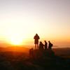 Five people standing on the summit of Boulder Hill, Puke Ariki in Belmont Regional Park at sunset.