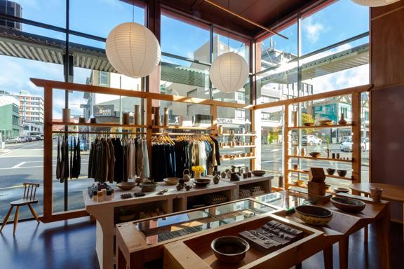 Inside Kaukau on ghuznee st, with large glass windows, clothes racks and wooden display tables.