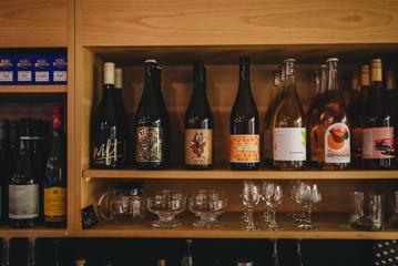 Wooden shelves with bottles of red wine and glassware at Supra restaurant.