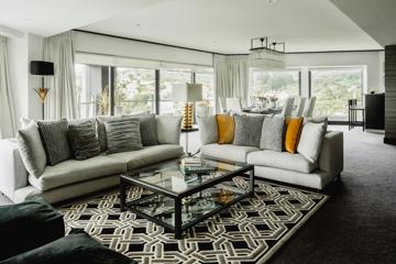 Inside a suite in the Bolton Hotel in Wellington with a glass coffee table, two couches and a dining table with six chairs in the background.