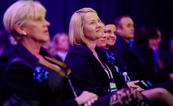 An audience, wearing business attire, sit and listen to a presentation at the Harcourts Conference at the TSB Arena in Wellington. 