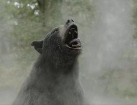 A still from Cocaine Bear. The black bear is roaring with its mouth open.