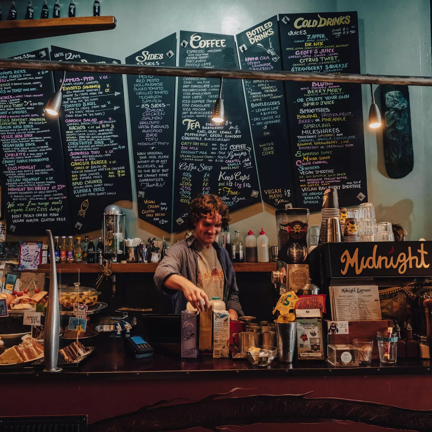 Front counter at Midnight Espresso with the menu displayed in colourful writing on large black chalkboards on the wall.