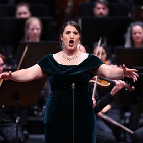 An opera singer performs with orchestral accompaniment.