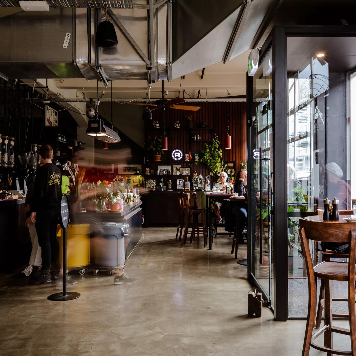 Inside Caffe L'affare, a café in Te Aro, Wellington. Sunlight fills the industrial-style space from the glass facade. 