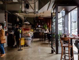 Inside Caffe L'affare, a café in Te Aro, Wellington. Sunlight fills the industrial-style space from the glass facade.