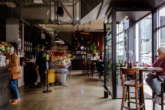 Inside Caffe L'affare, a café in Te Aro, Wellington. Sunlight fills the industrial-style space from the glass facade.