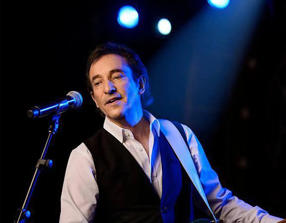 David Pomeranz plays guitar and sings on stage.