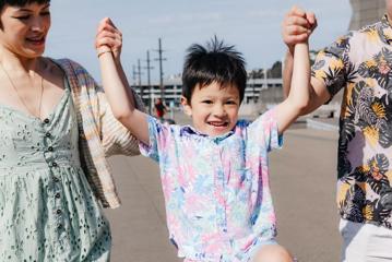 A child is swung by the arms on 2 adults on the Wellington Waterfront.