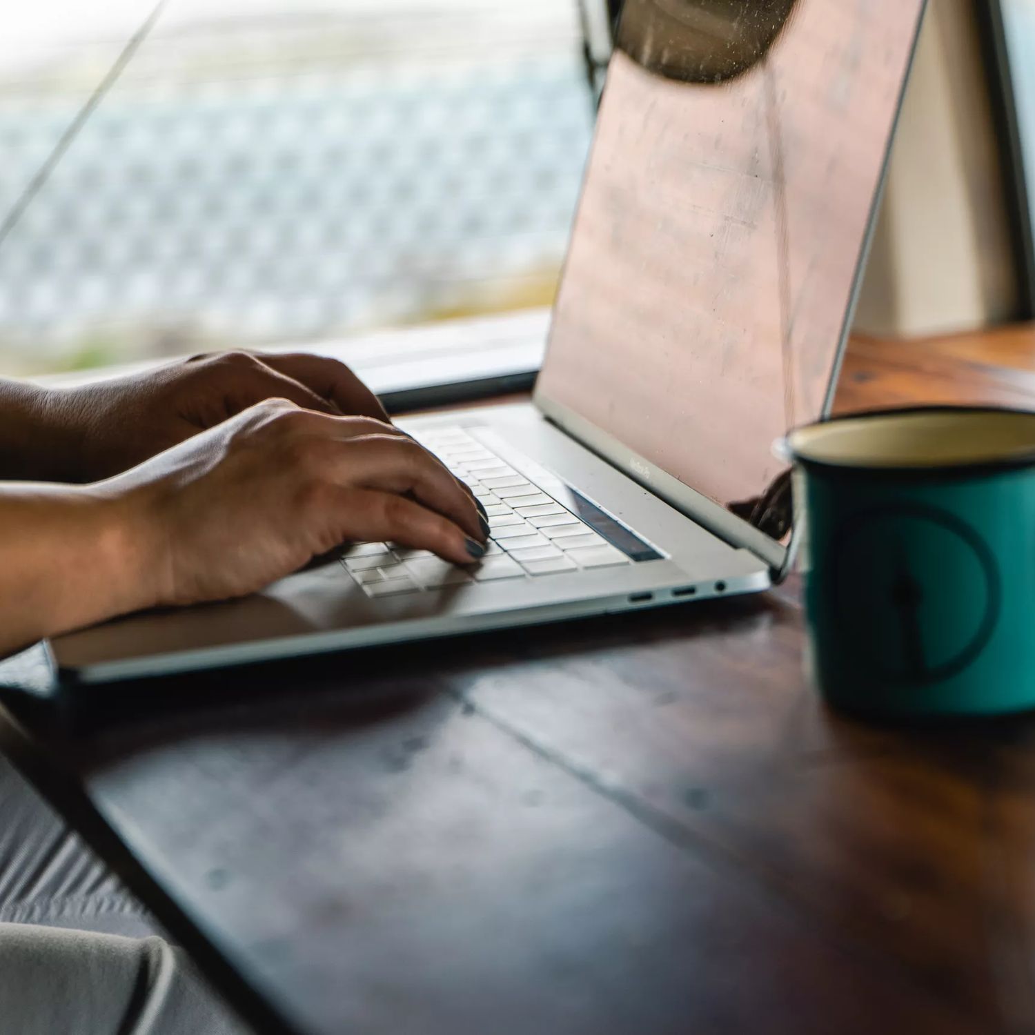 Bianca Grizhar tying on a laptop with a blue coffee mug.