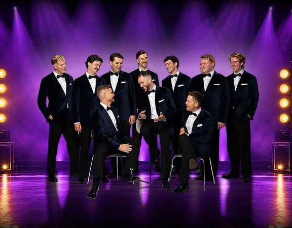 The Ten Tenors perform on stage under purple lighting, with ten singers in formal black suits arranged around seated and standing positions.