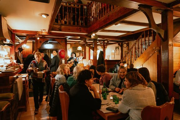 The rustic interior of Cicio Cacio, an Italian restaurant in Newtown, Wellington, is full of people enjoying food and drinks.