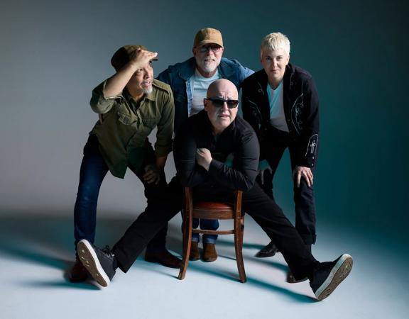 The four members of the Pixies pose in front of a grey background.