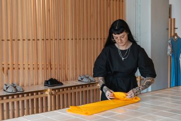 A person folds a yellow dress.