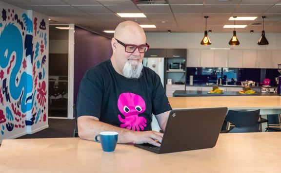 Portrait of Ari Sargent from Octopus Energy working on a laptop.