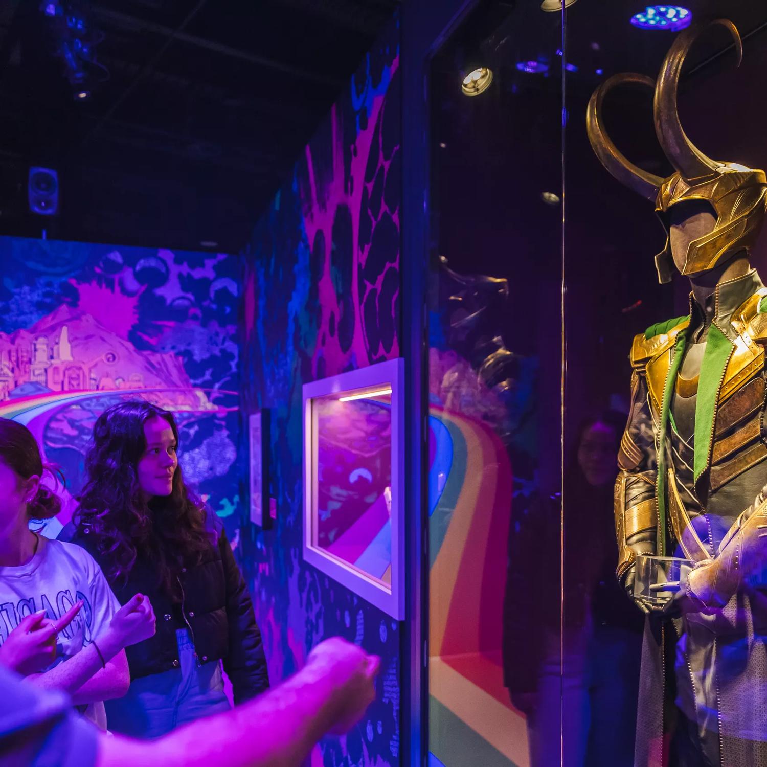 A group of friends look at one of the costumes on display at Marvel Earth's Mightiest Exhibition.