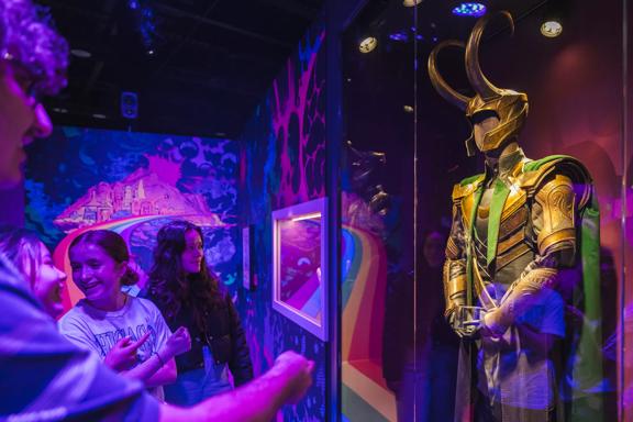 A group of friends look at one of the costumes on display at Marvel Earth's Mightiest Exhibition.