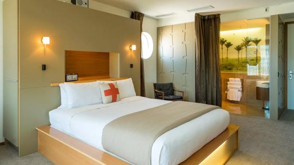 The deluxe room inside Ohtel, with a large bed in the centre of the room and large bathroom seen in the back.