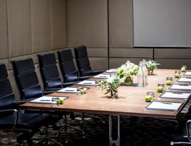 A meeting table inside Aurora room Intercontinental Wellington,  set with pen and papers, glasses and an apple each.