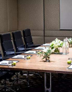 A meeting table inside Aurora room Intercontinental Wellington,  set with pen and papers, glasses and an apple each.