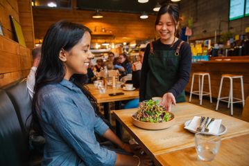 A server delivers a salad to a customer at The Hanger café.
