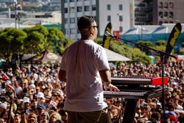 A performer at the Park stage at Jim beam Home Grown 2023 playing the keyboard and singing  to a crowd of thousands.