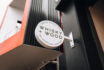 The circular white sign outside of Whisky and Wood, an event venue located at 60 Cambridge Terrace in Te Aro, Wellington.