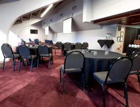 In the Longroom at the Basin Reserve circular tables covered in black table cloths and surrounded by chairs fill the space. As bar is off to the right.