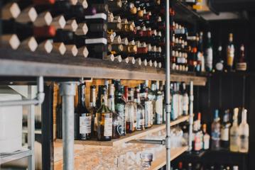 Wine and liquor bottles stored on wooden shelves lining the back wall of Noble Rot wine bar.