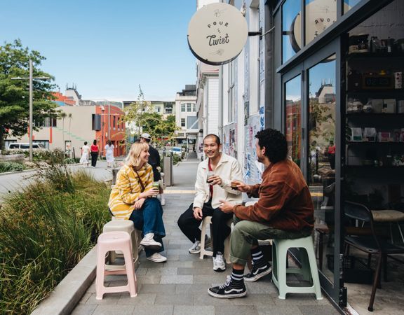 Three friends have coffee outside Pour & Twist, a café in Te Aro, Wellington.