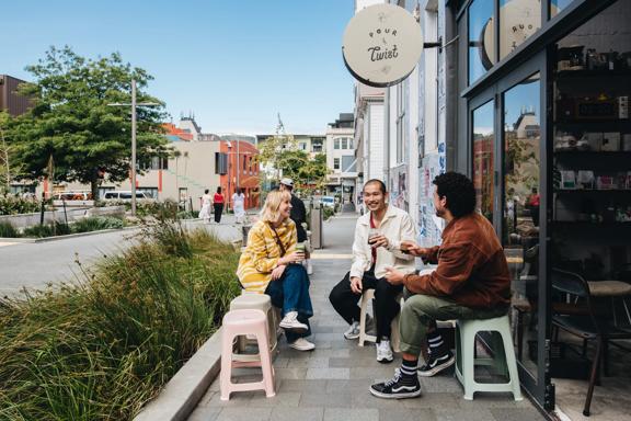 Three friends have coffee outside Pour & Twist, a café in Te Aro, Wellington.