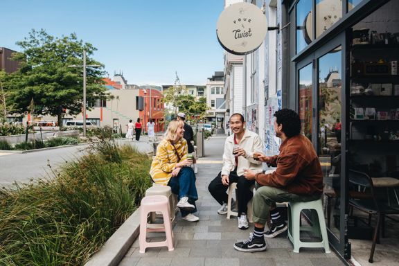 Three friends have coffee outside Pour & Twist, a café in Te Aro, Wellington.