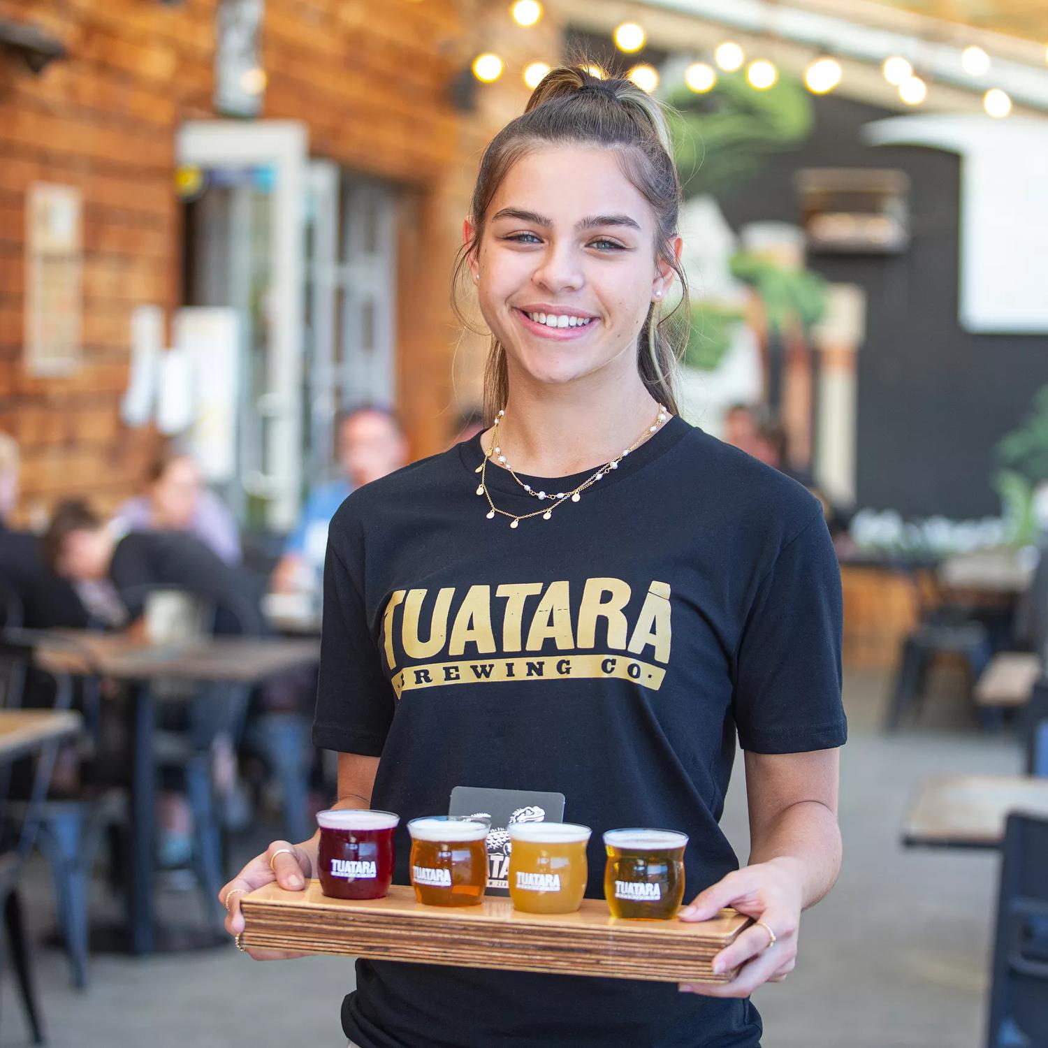 A waiter holding a tasting tray of beers at Tuatara.