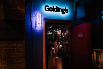 The front door at Golding's Free Dive at night, a bar located in Te Aro, Wellington. The sign is illuminated with neon lights.