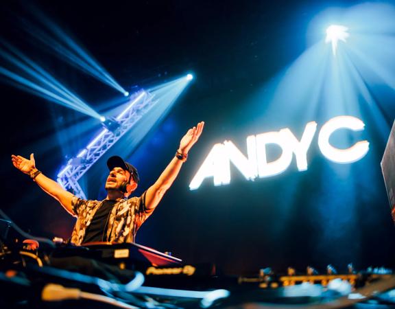 Dj Andy C with his hands on the air on stage.