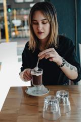 A person wearing a black top enjoys a coffee at Scopa, an Italian restaurant in Te Aro, Wellington.