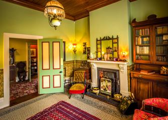 A room inside Katherine Mansfield House & Garden in Wellington, New Zealand.  The walls are green and the furniture and decorations are from the 1800s.