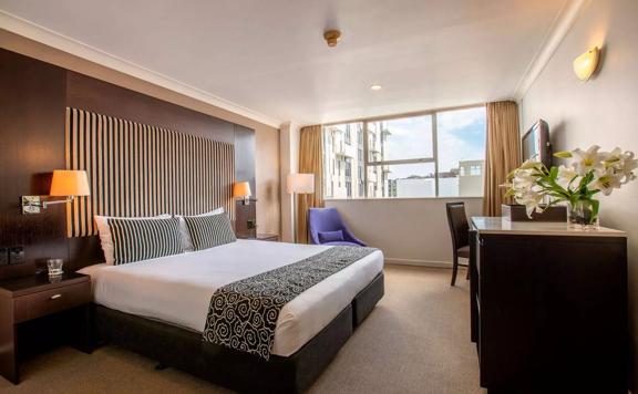 A room inside Mercure Hotel, with a bed, desk, and TV.