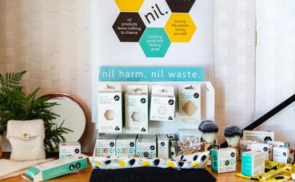 A display case on a table holds several eco-beauty products from the nil brand. Products include cotton buds, facecloths, and make up removers.