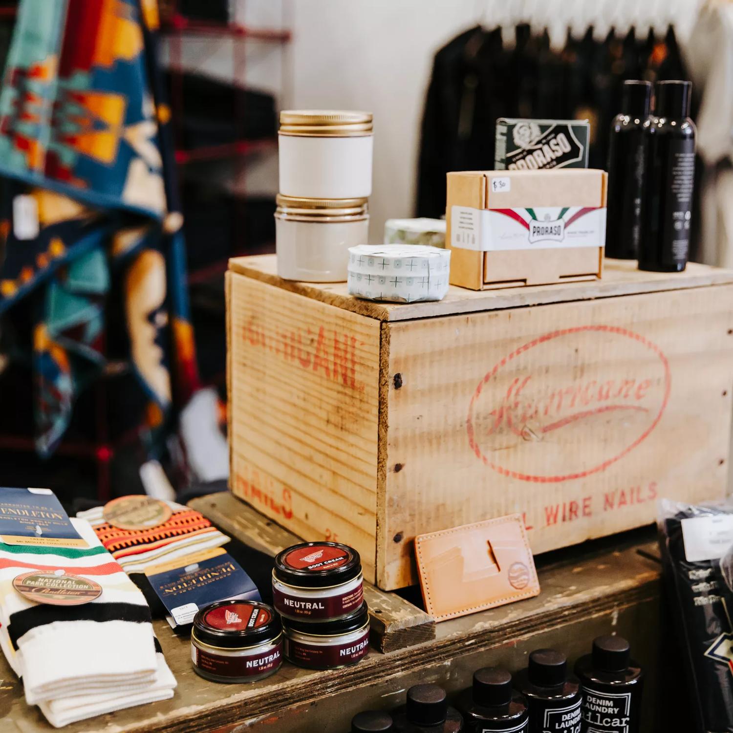 Socks and skinscare products sitting on a wooden display table in a store.