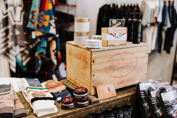 Socks and skinscare products sitting on a wooden display table in a store.