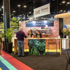 The Tākina stall set up at a convention, with people walking around.