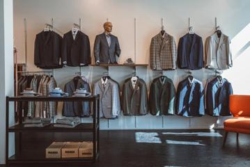 Inside Mandatory Menswear Ltd, a men's clothing store in Te Aro, Wellington. The modern space has white walls, black floors, suit jackets hanging against the wall and a mannequin.