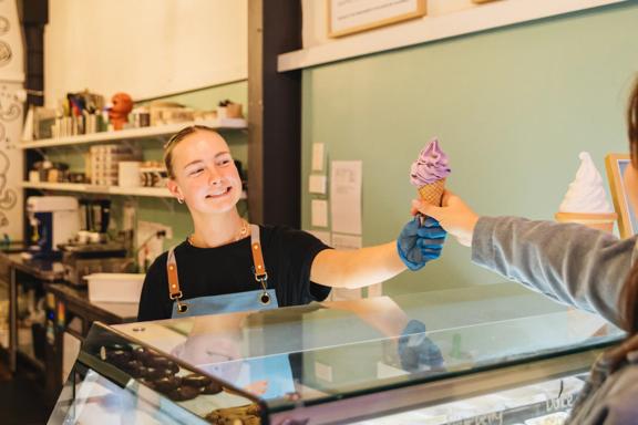 A Zelati employee gives an ube soft serve to a customer.