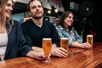 Three people enjoy pints of craft beer at the bar at Garage Project Taproom in Aro Valley, Wellington.