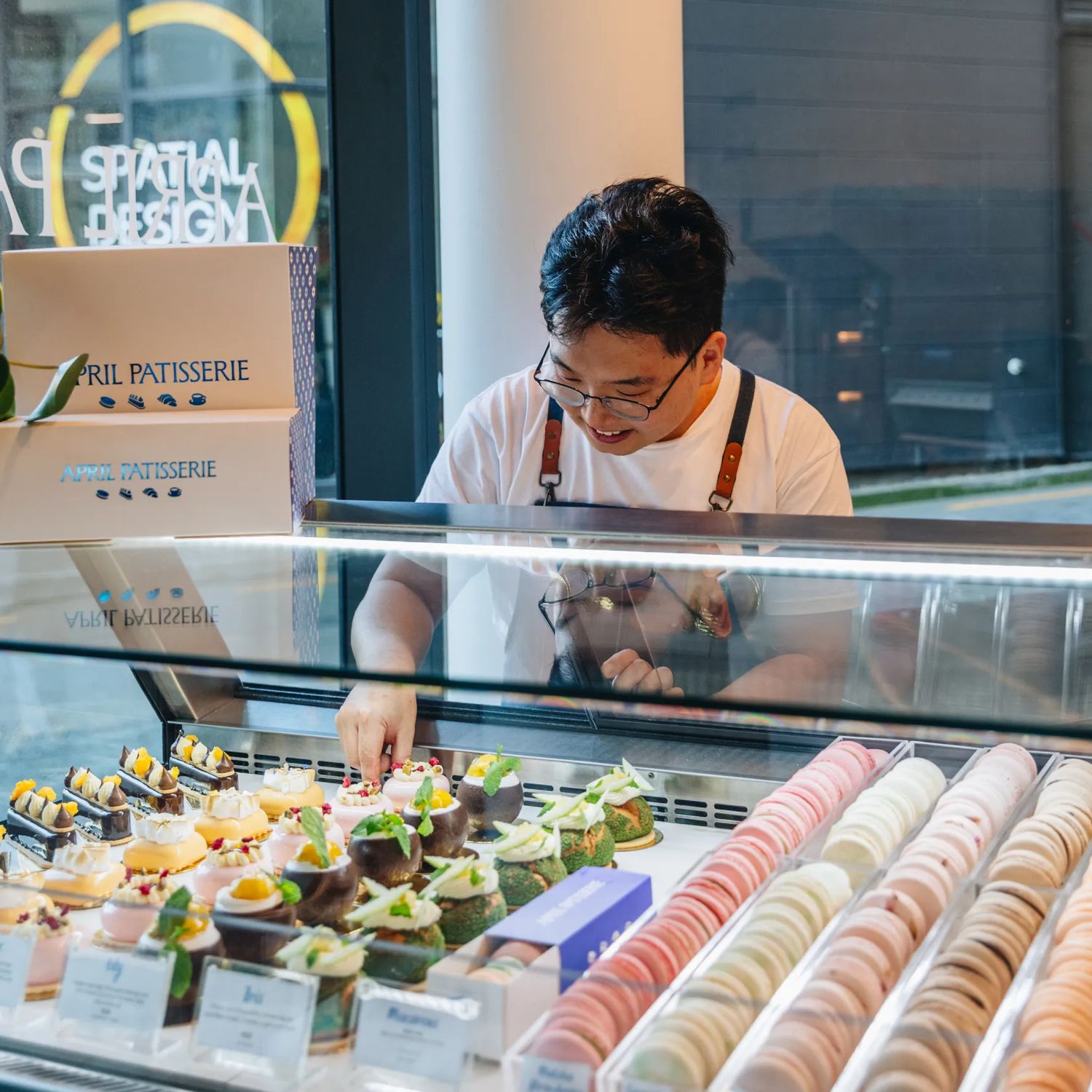 A staff member arranges desserts in the display case at April Patisserie.